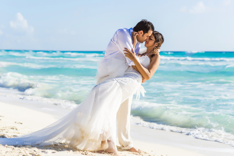 married couple kissing on beach