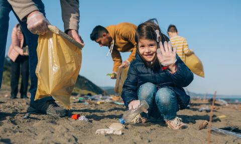 Family picking up trash on the beach.