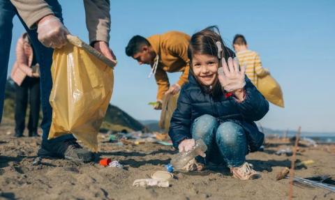 Family picking up trash on the beach.