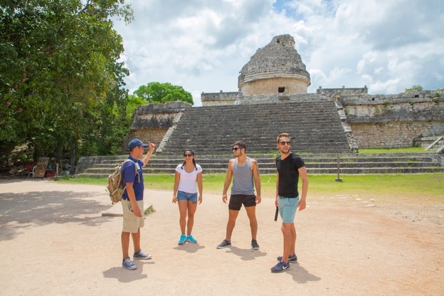 4 people standing outside chichen itza ruins