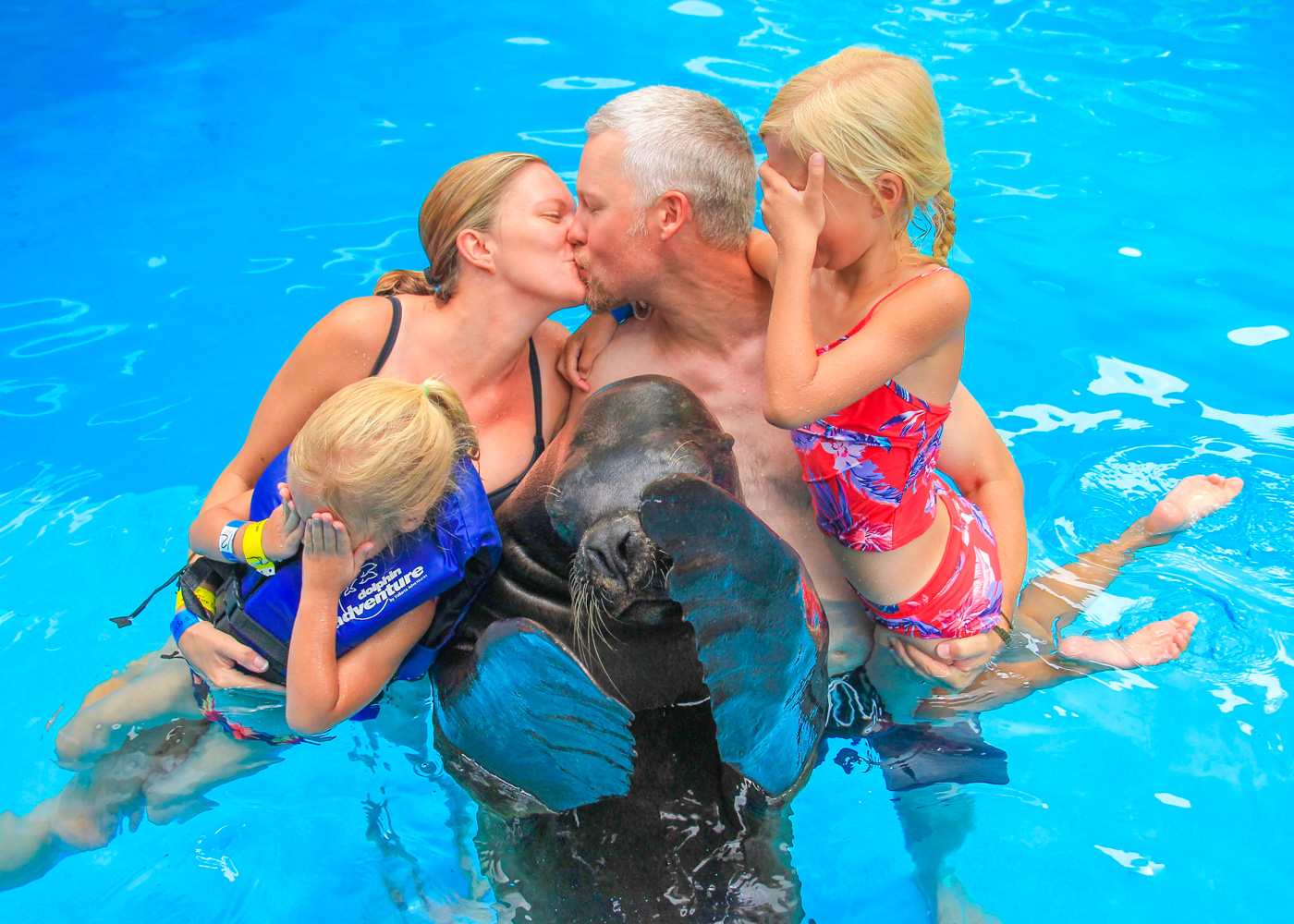Parents kissing while kids and sea lion cover their eyes