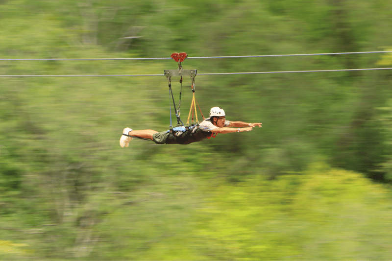 man flying through the air on a zipline while having fun