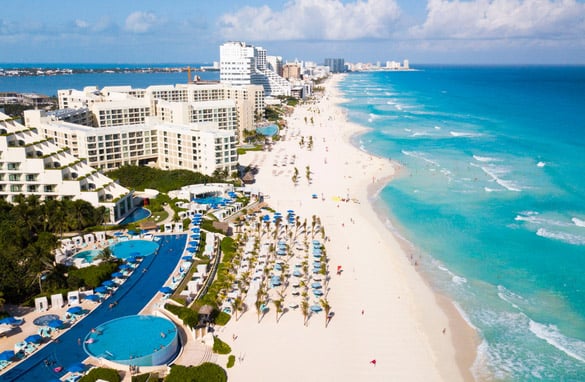 Aerial view of Cancun’s shoreline filled with resorts and highrises.