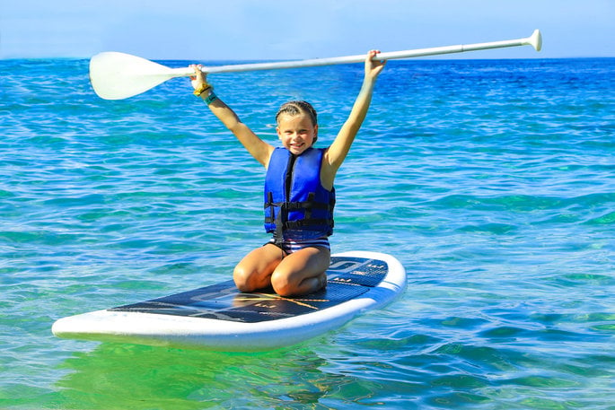 Girl kneeling on a paddle board 