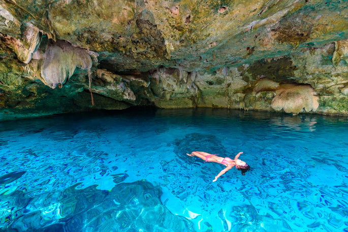 Woman swimming in a cenote during an excursion with Cancun Adventures on her romantic couples vacation