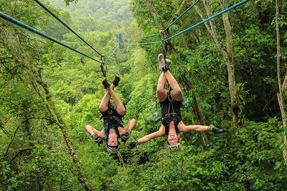 A couple hanging upside down on a zipline