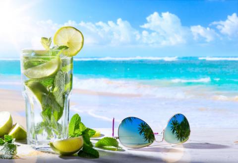 glass of lemon lime water on a cancun beach next sunglasses