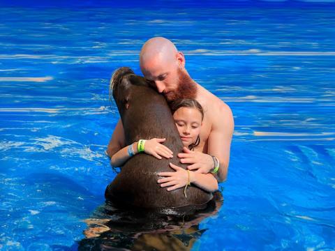 Man and girl hugging dolphin