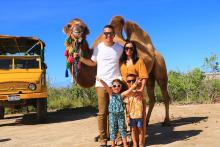 Family of four posing with a camel on our Outback & Camel Safari Tour.